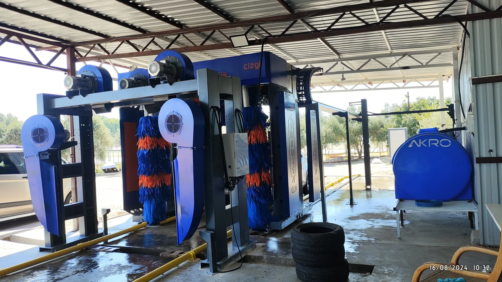 Rollover car wash machine under a canopy, seen from outside